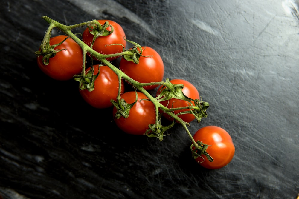 a bunch of tomatoes sitting on top of a black counter
