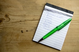 a notepad with a green pen sitting on top of it