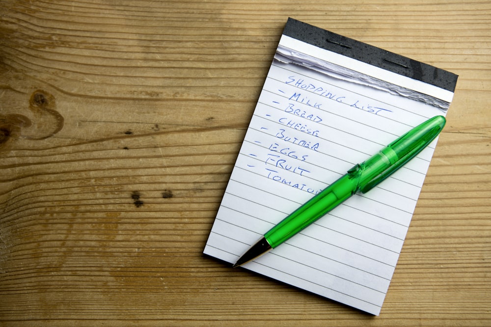 um bloco de notas com uma caneta verde sentada em cima dele