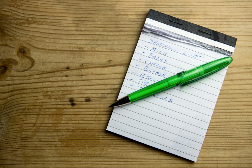 a green pen sitting on top of a piece of paper