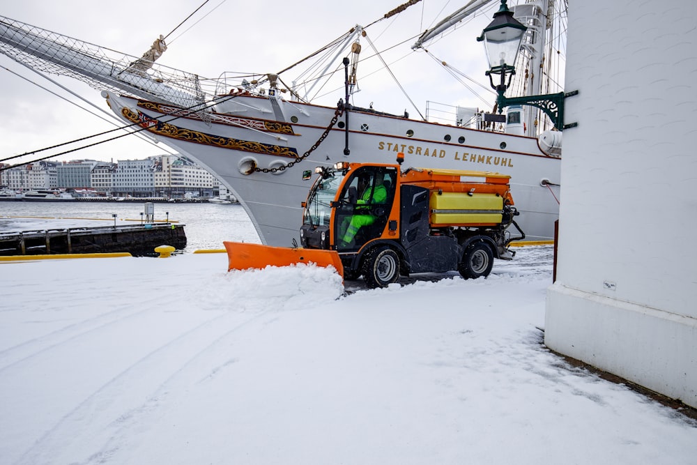a tractor is parked in front of a boat in the snow