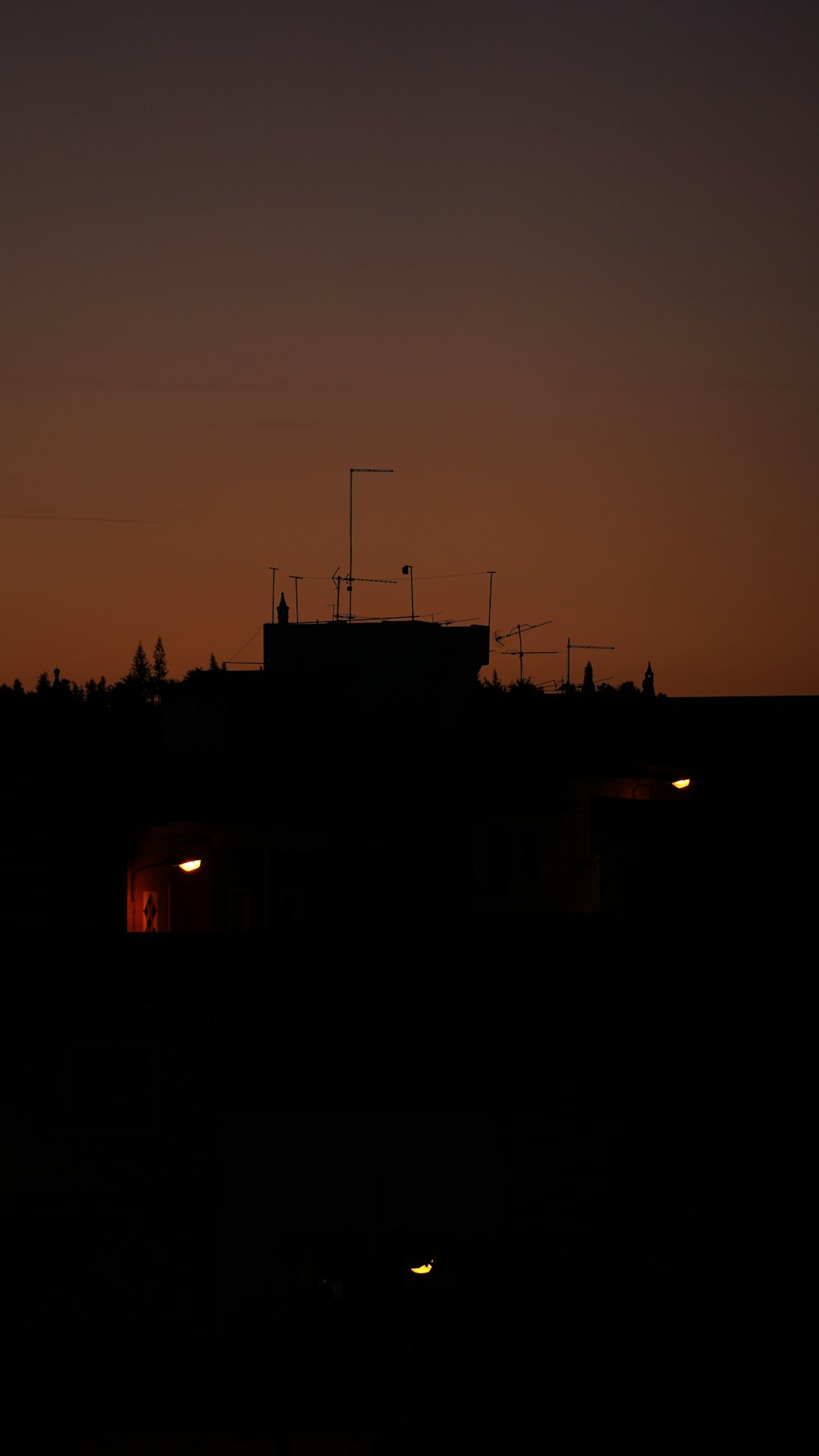 a silhouette of a building at night with the moon in the distance