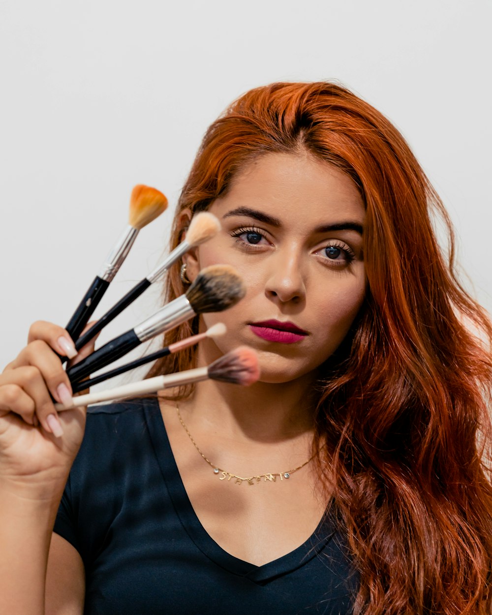 a woman holding a bunch of makeup brushes