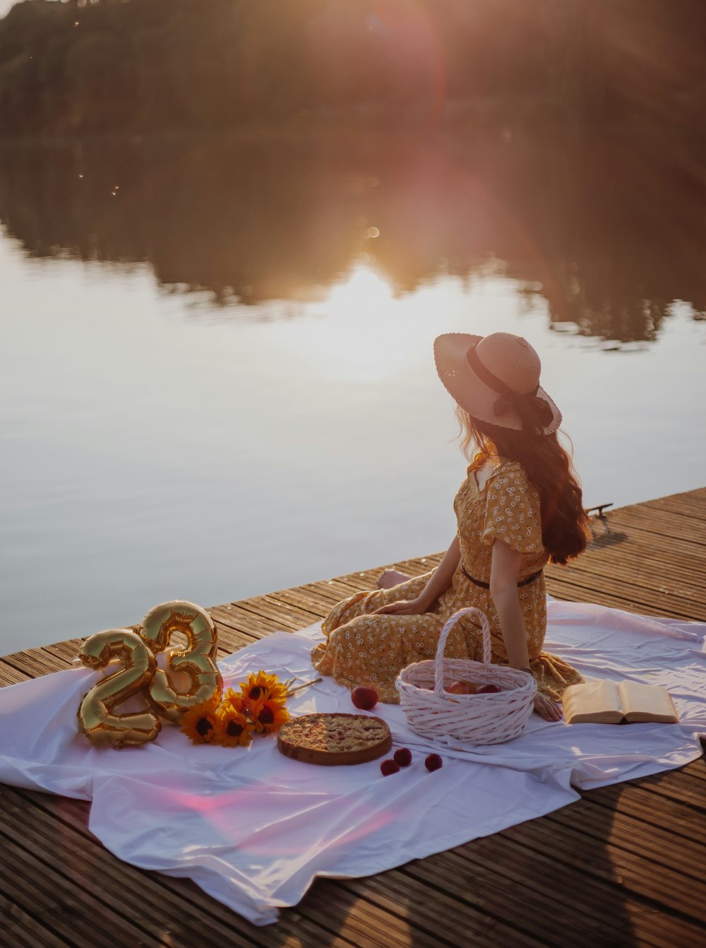 a woman sitting on a blanket next to a lake