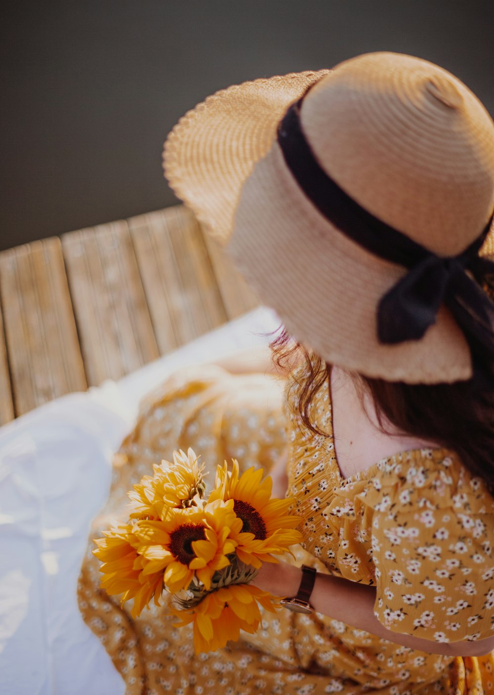 a woman sitting on a bed holding a sunflower