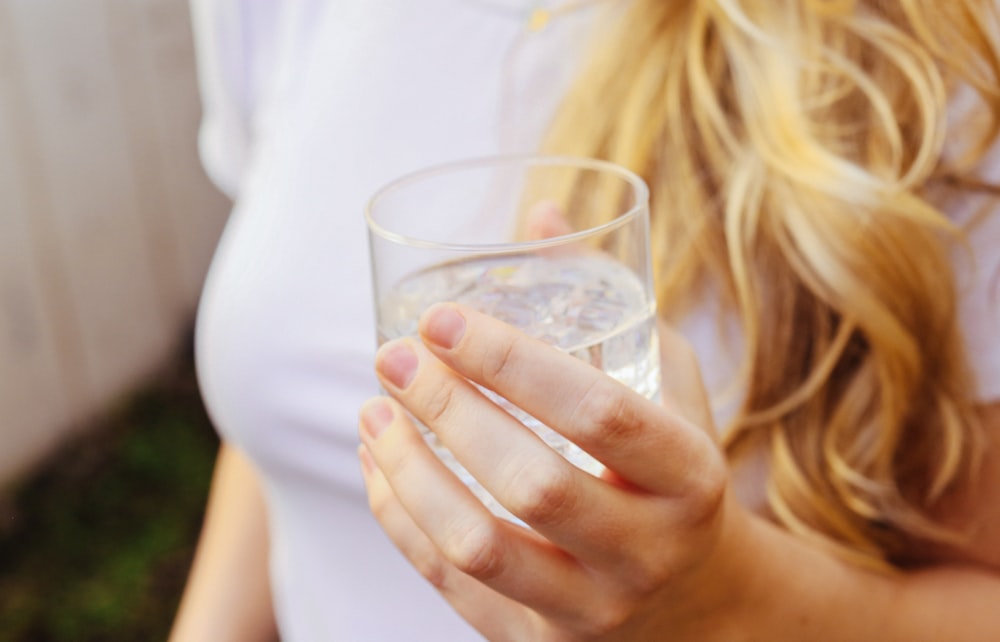 uma mulher segurando um copo de água em sua mão
