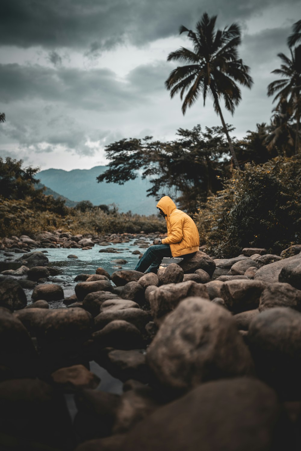 a person sitting on rocks near a river