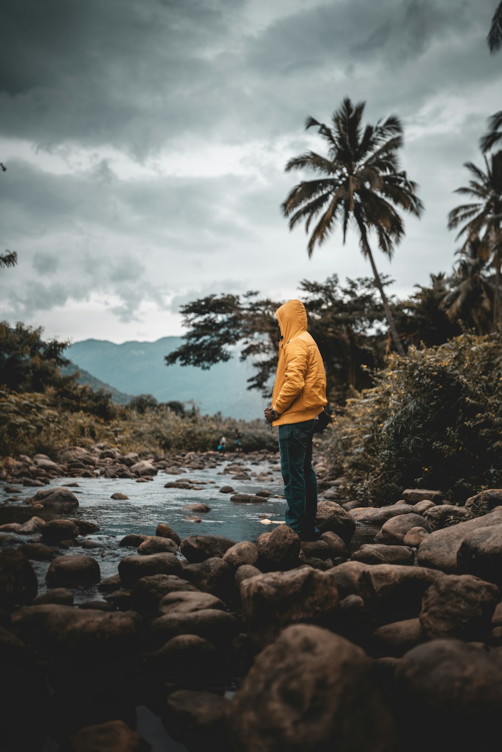 a person in a yellow jacket standing on rocks