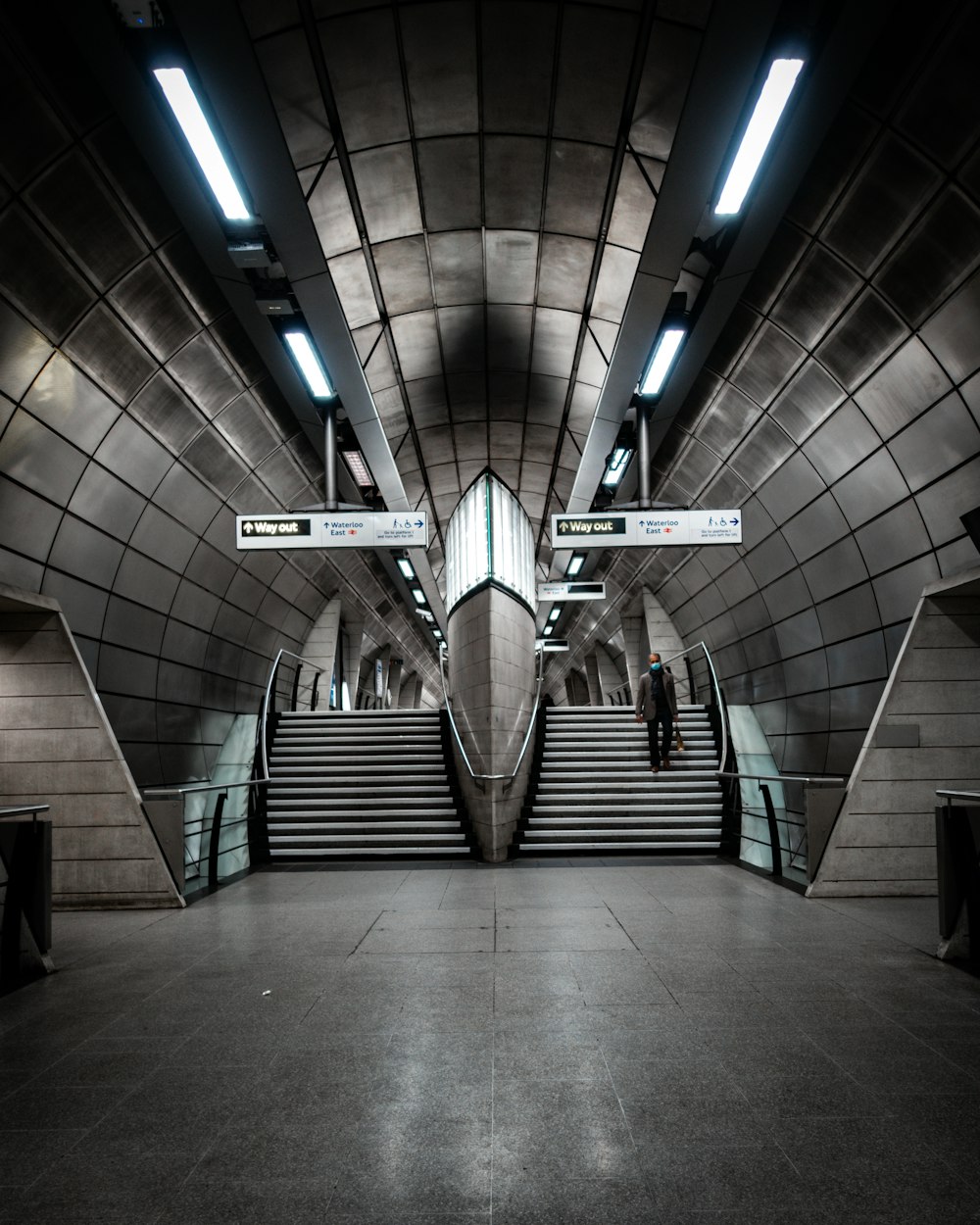 a person standing on a set of stairs in a subway station