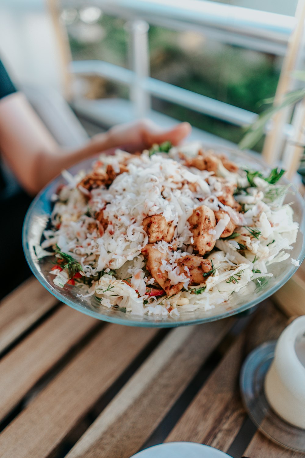 a person holding a plate of food on a table