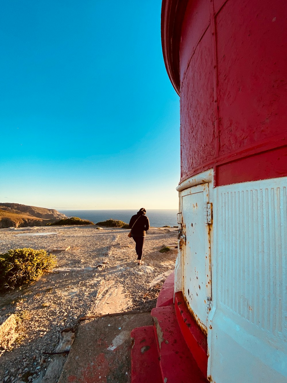 a person walking down a path near a red structure