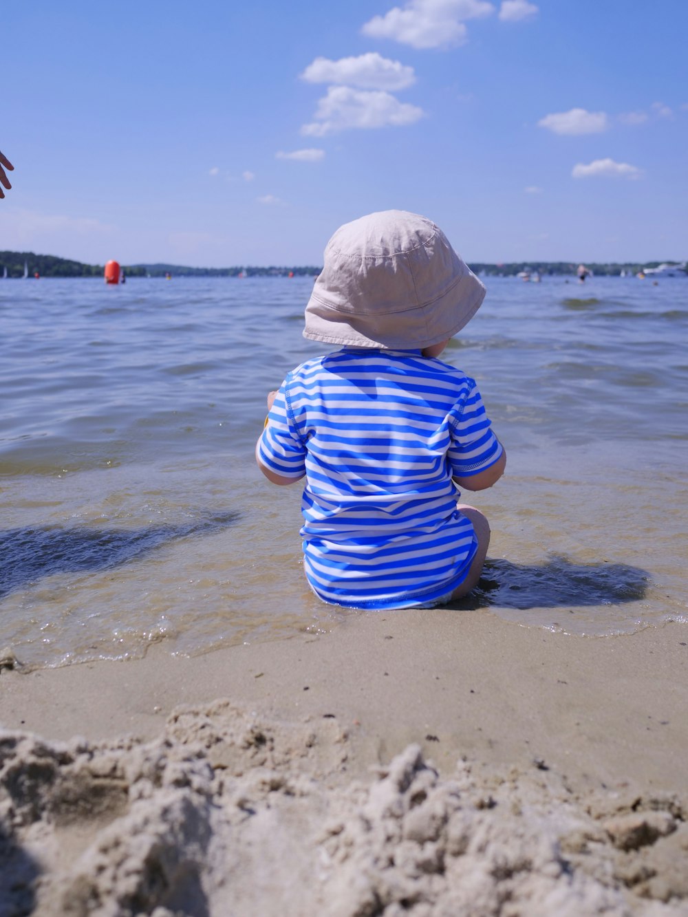 um menino sentado na areia na praia