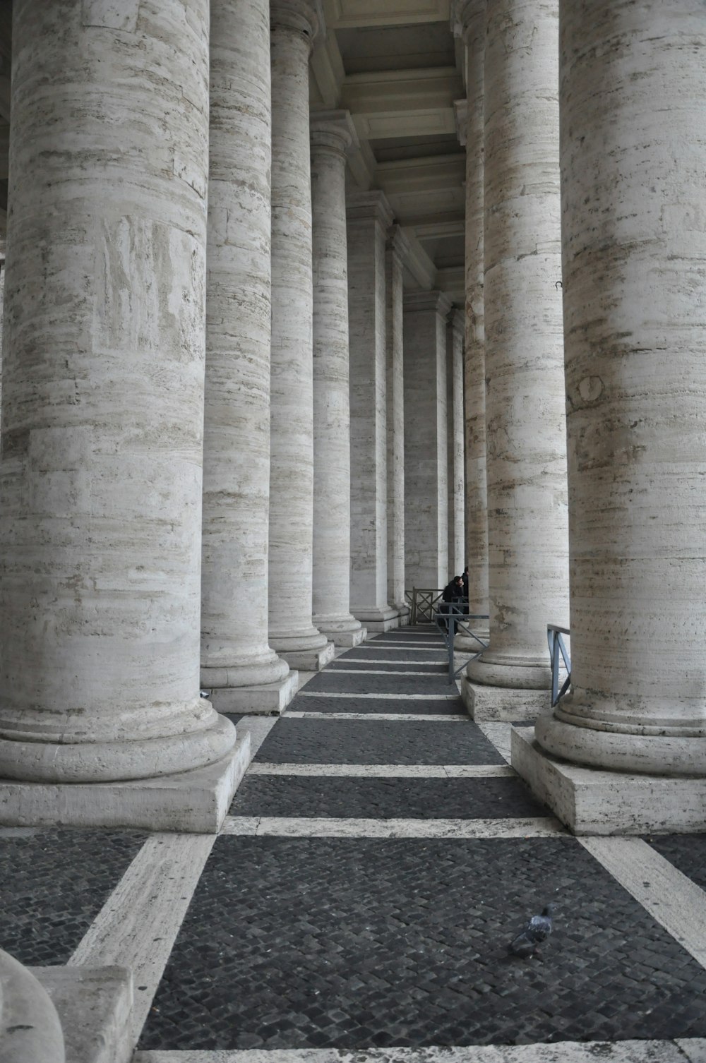 a row of white pillars with a person sitting on one of them