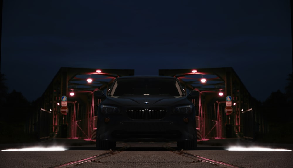 a car parked in front of a bridge at night