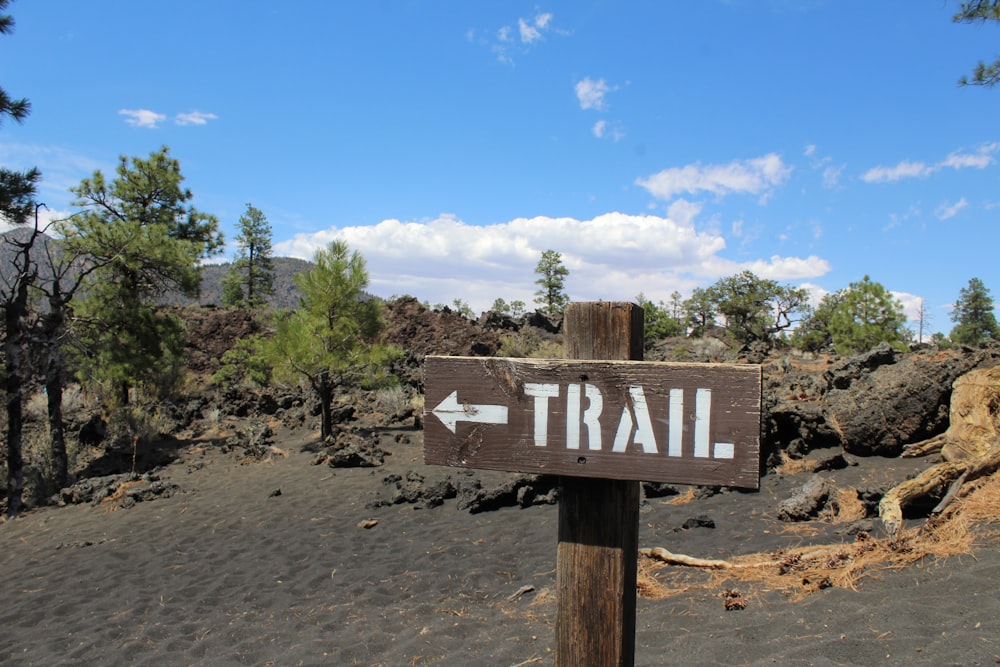 a wooden sign pointing to a trail in the mountains