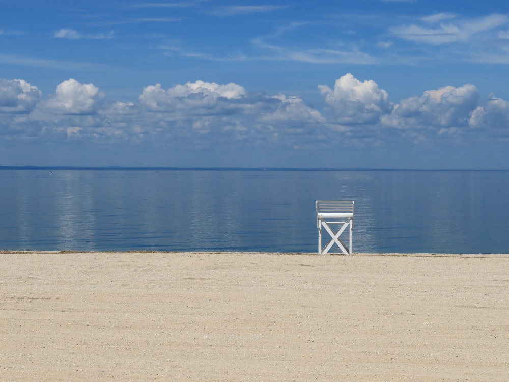 a white chair sitting on top of a sandy beach