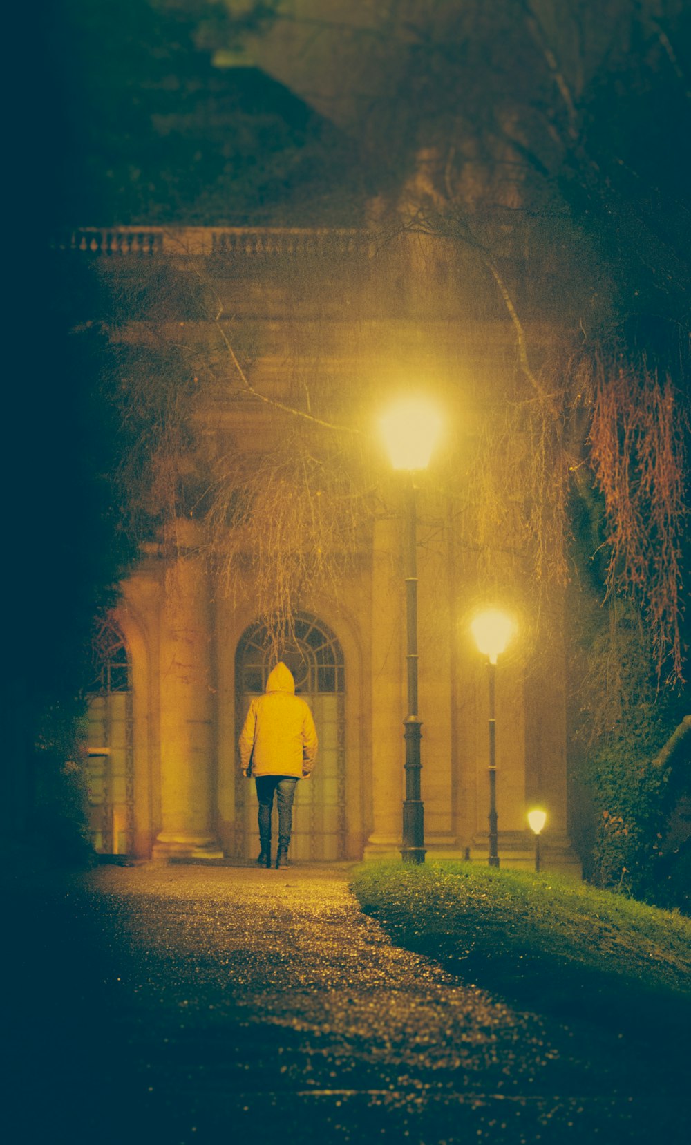 a person in a yellow jacket walking down a street at night