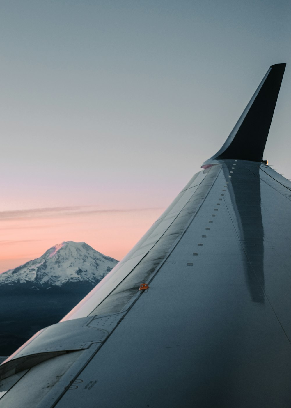 the wing of an airplane with a mountain in the background