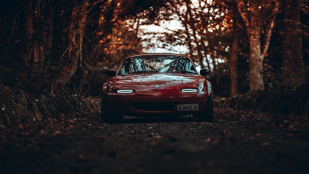 a red sports car parked in a wooded area