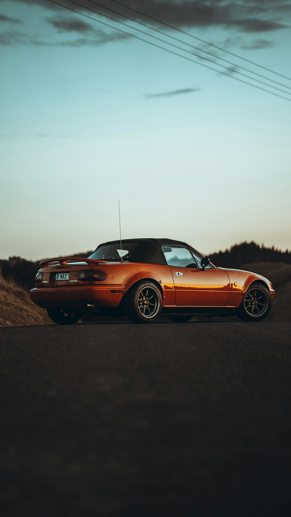 an orange sports car parked on the side of the road