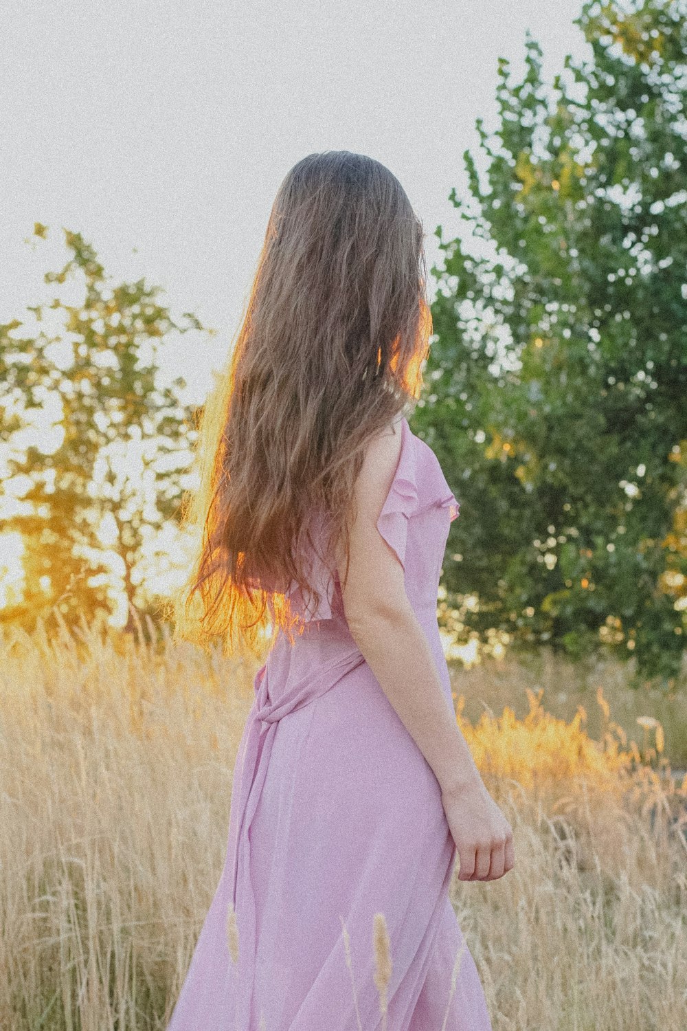 Eine Frau in einem lila Kleid steht auf einem Feld