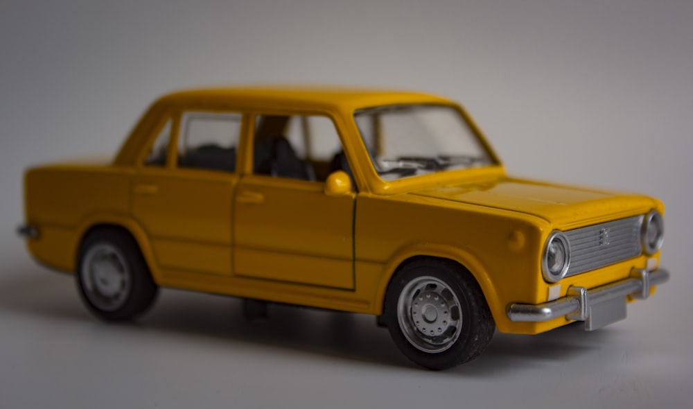 um carro de brinquedo amarelo sentado em cima de uma mesa branca