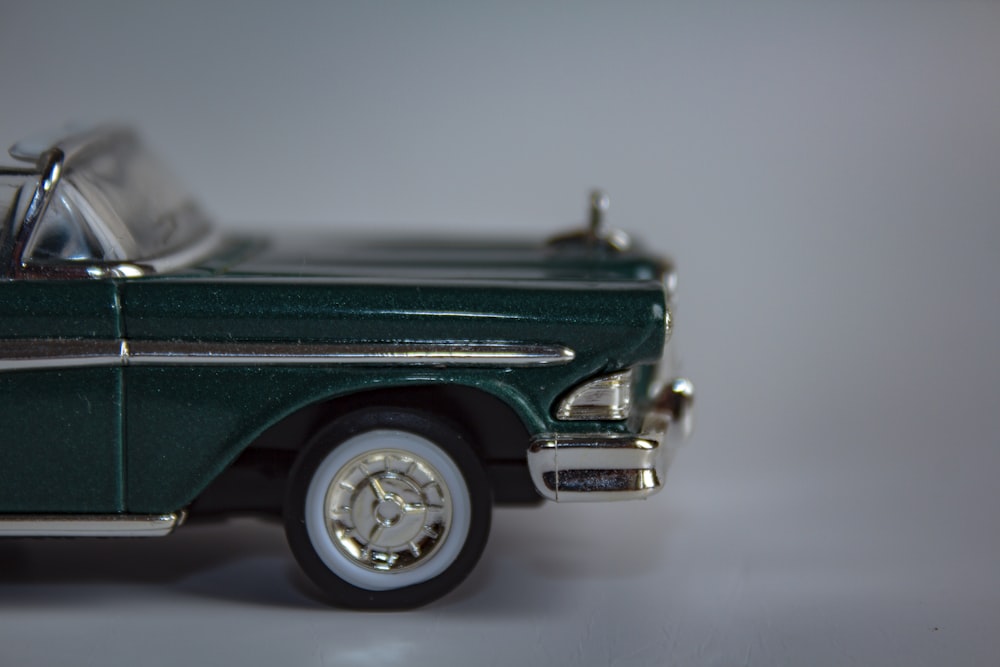 a green toy car on a white surface