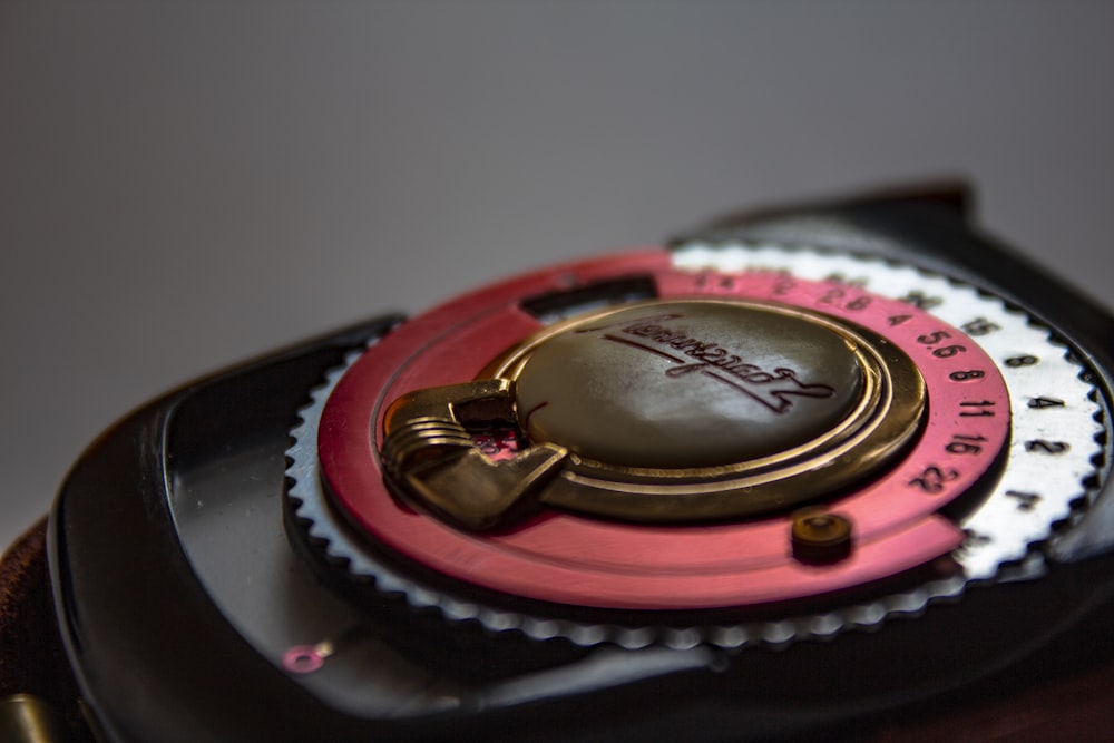 a close up of a watch with a pink and black case