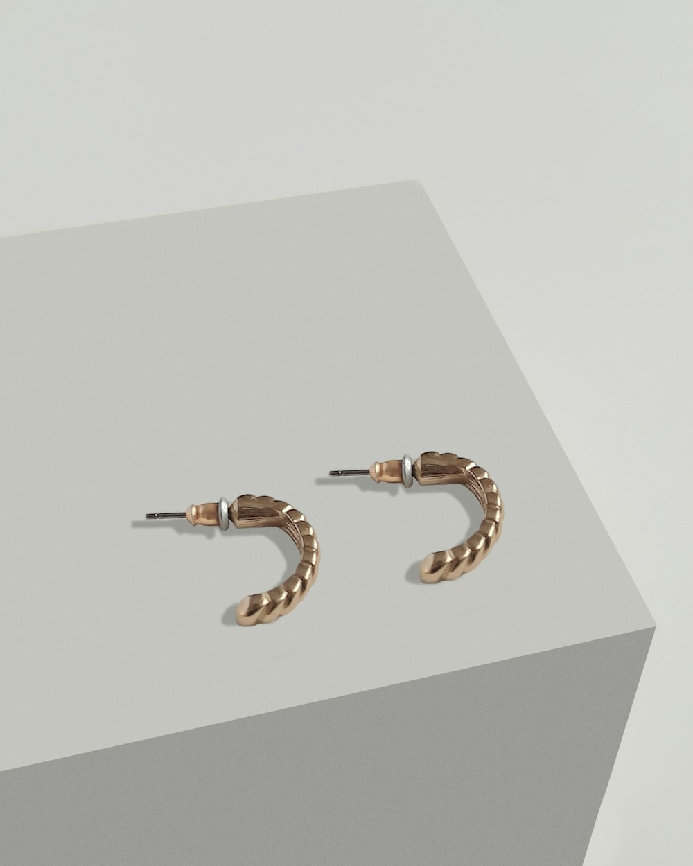 a pair of gold hoop earrings on a white surface