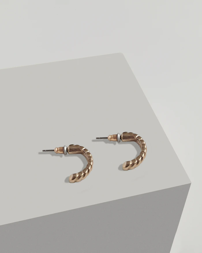 Minimalist gold hoop earrings on a white surface