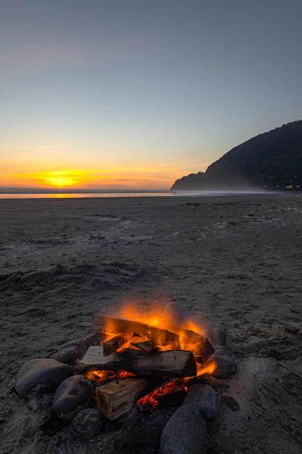 Sunset view over a calm beach with travelers enjoying a bonfire