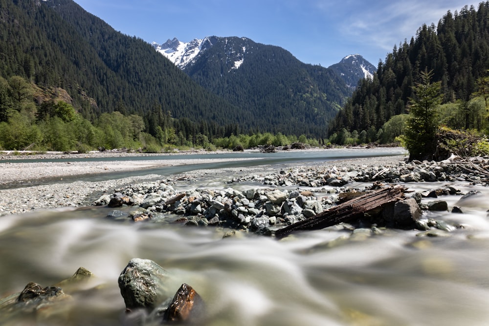 a river with rocks in it and mountains in the background