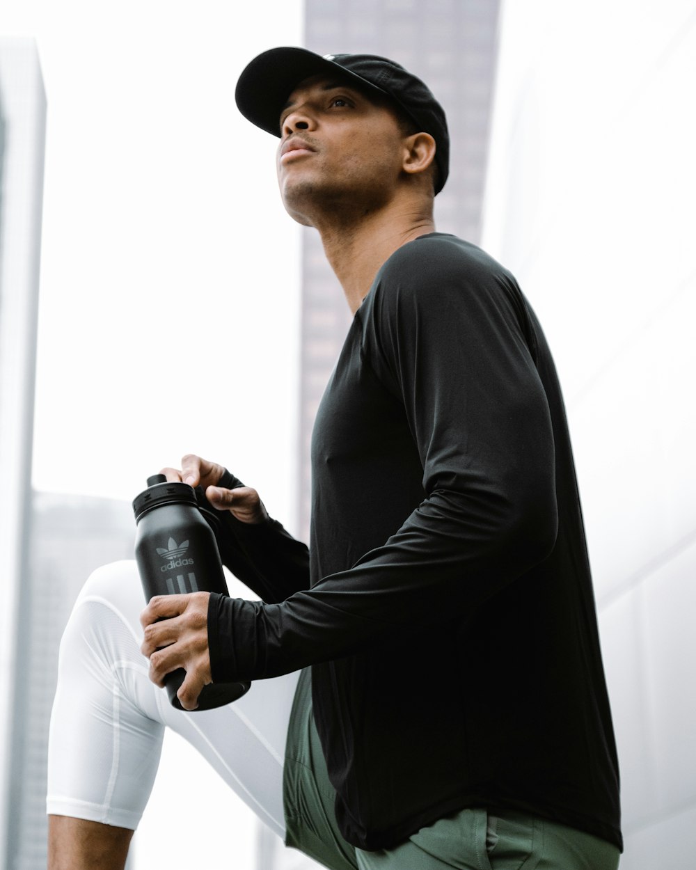 a man in black shirt and white pants holding a black water bottle