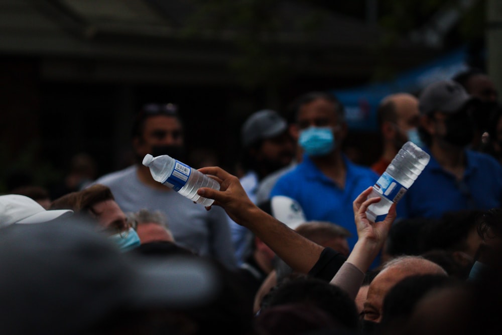 a crowd of people wearing face masks and holding up water bottles