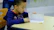 A happy child working on math exercises with a supportive tutor in a cozy learning environment.