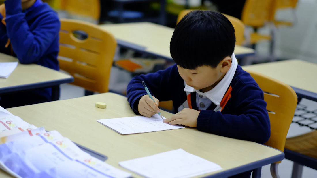 Student writing at desk