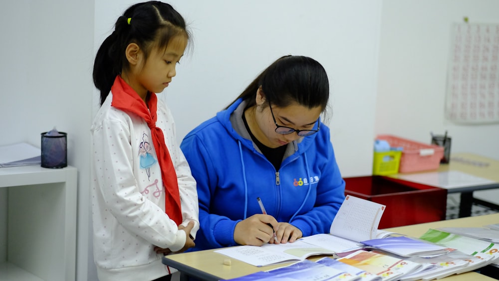 a woman and a girl are doing something on a desk