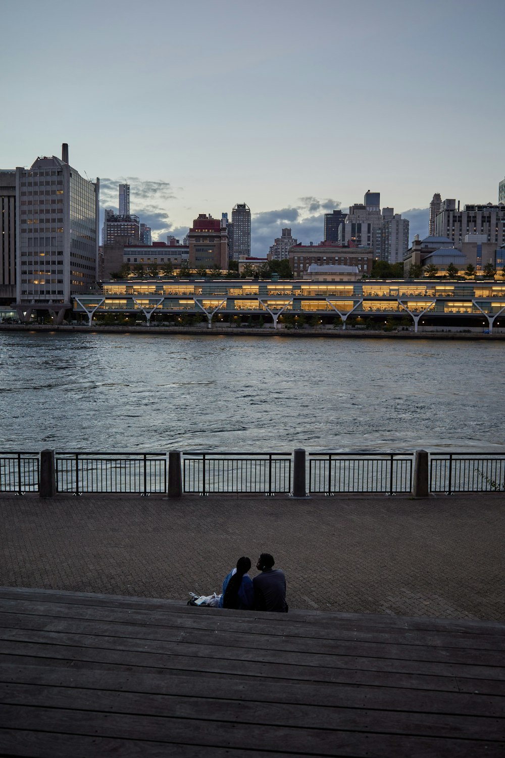 two people sitting on a bench near a body of water