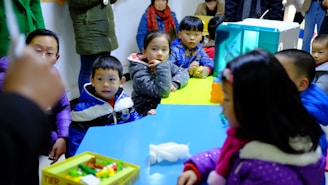 a group of children sitting around a blue table