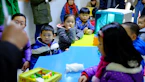 a group of children sitting around a blue table