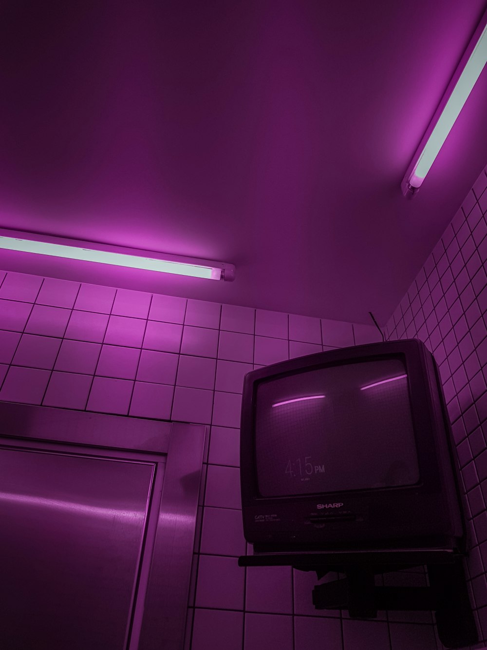 uma TV sentada em cima de um suporte em um banheiro
