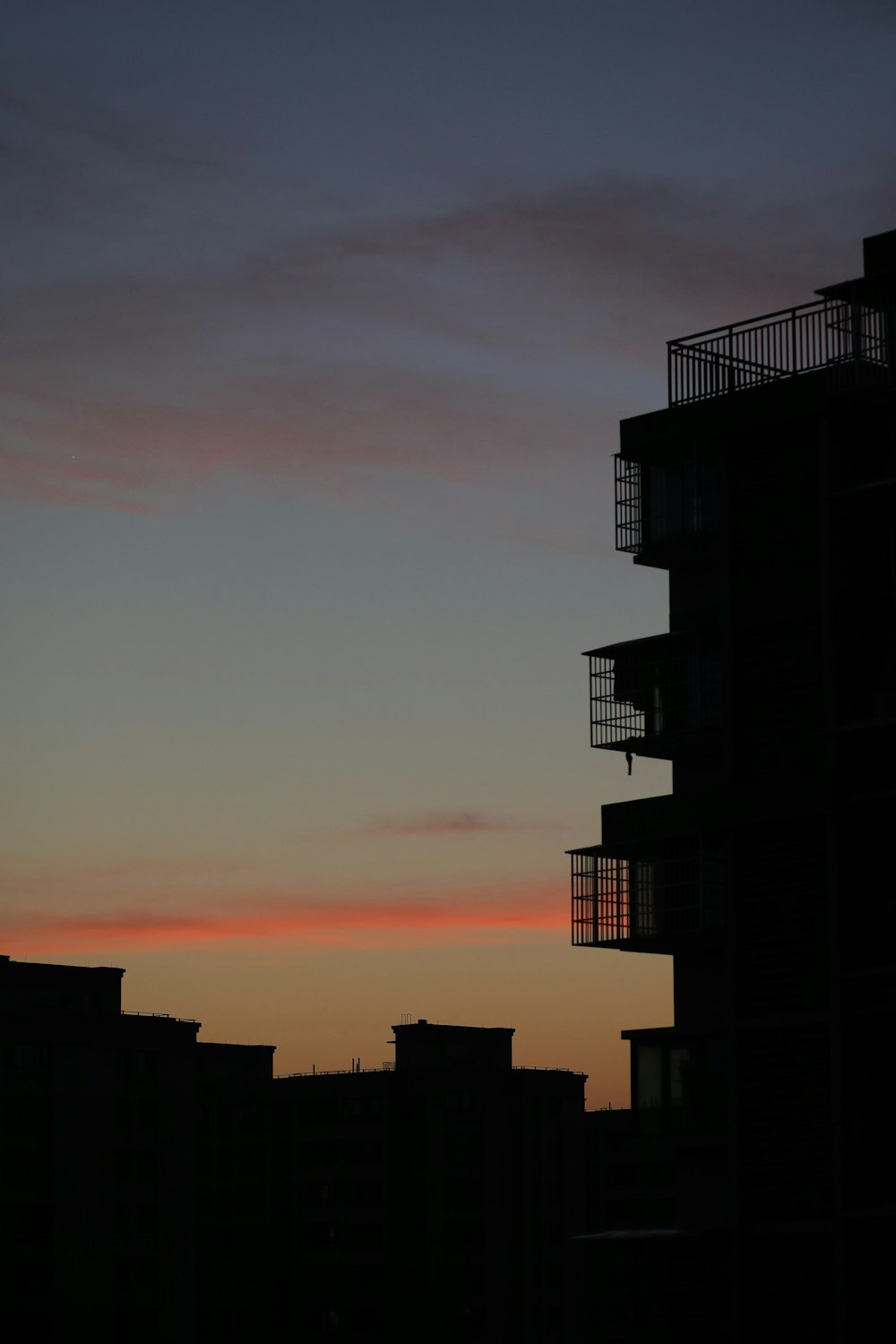 a building with balconies and a sunset in the background