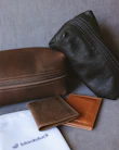 A collection of handcrafted leather wallets in various earthy tones arranged neatly on a linen cloth.
