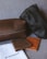 The image features two leather pouches, one dark brown and one black, positioned on a fabric surface. In front of them are two leather wallets, one brown and the other tan, along with a branded white cloth bag labeled 'blackduck'. The items appear to be high-quality leather goods.