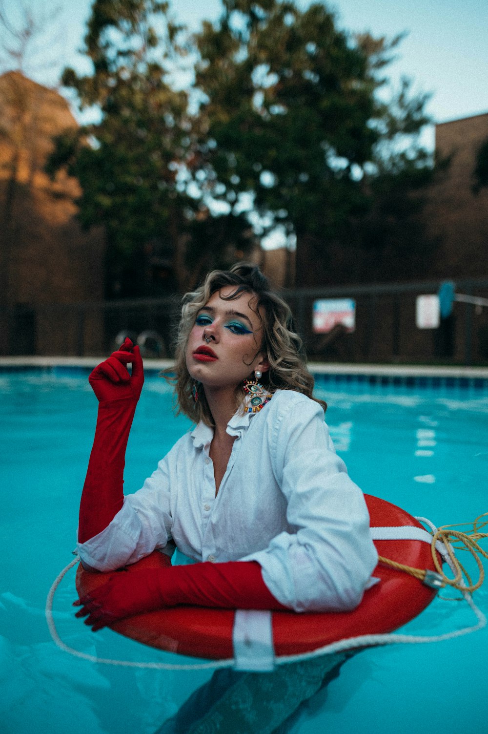 a woman sitting on a life preserver in a pool