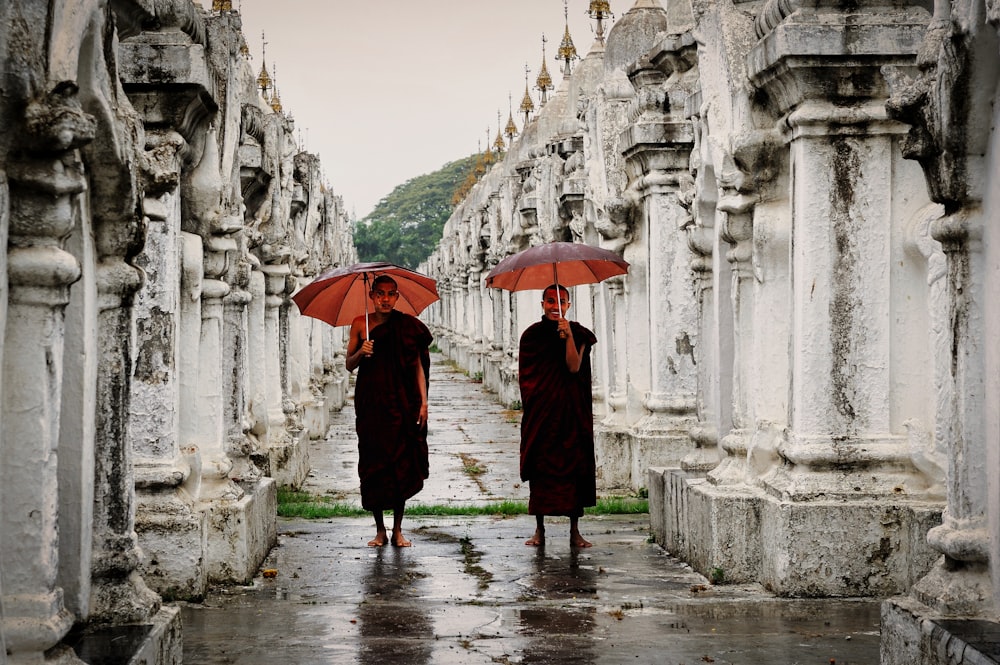 person in black coat holding umbrella walking on sidewalk during daytime