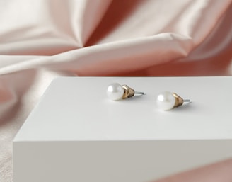 a pair of pearl earrings sitting on top of a white box
