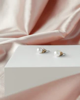 Classic pearl studs paired with a delicate lace fabric background.