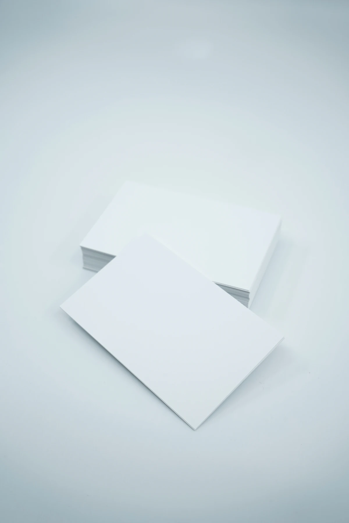Dos hojas de papel en blanco apiladas sobre fondo blanco