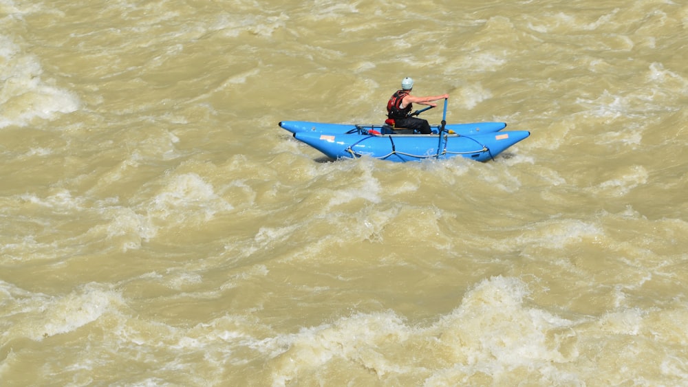 a man in a blue kayak on a river